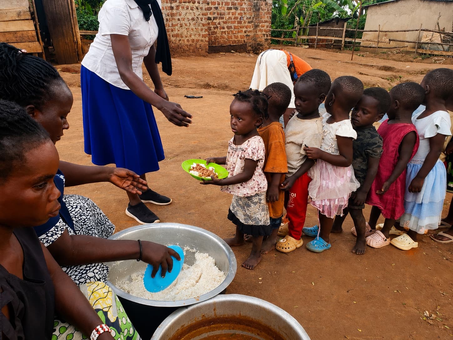 Children receiving a freshly prepared meal during a community food programme in Uganda